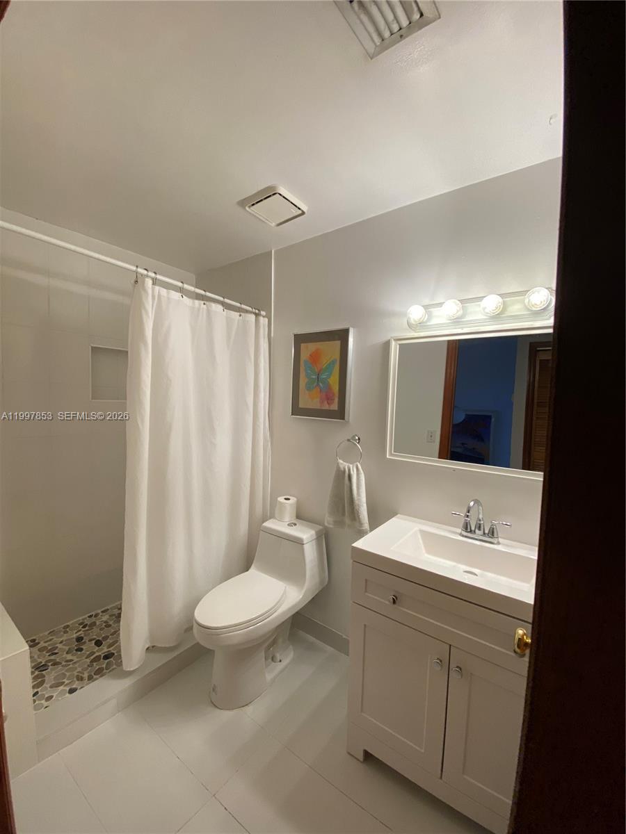 2425 Southwest 27th Avenue, Unit 1008 Miami, FL 33145 - Photo 14 of 20 a spacious bathroom with a double vanity sink toilet mirror and shower