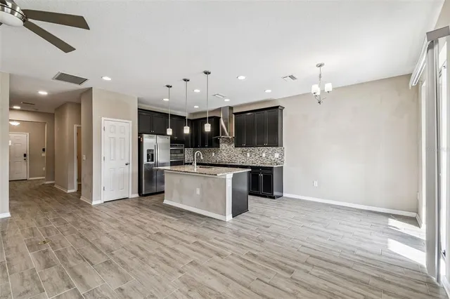 a large kitchen with stainless steel appliances a large counter top a stove and a wooden floors