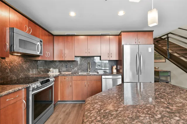 a kitchen with stainless steel appliances granite countertop a refrigerator a stove microwave and sink