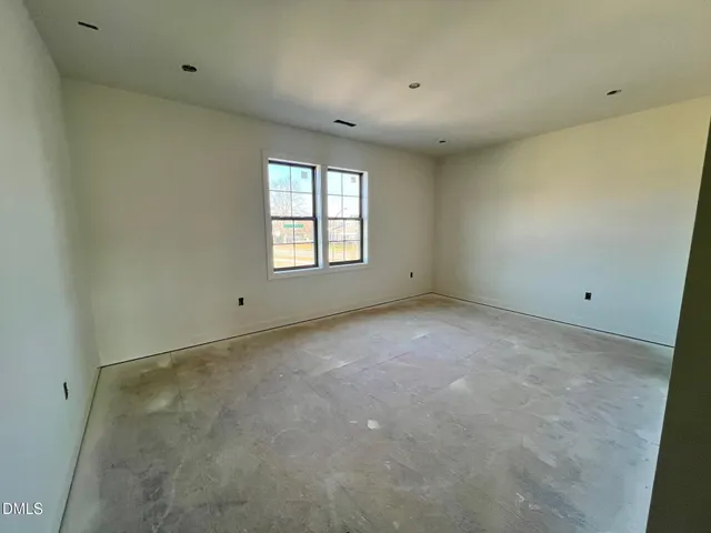 a view of an empty room and kitchen with wooden floor and a window