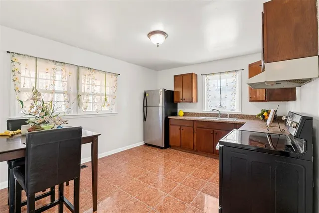 a kitchen with granite countertop a refrigerator stove sink and cabinets