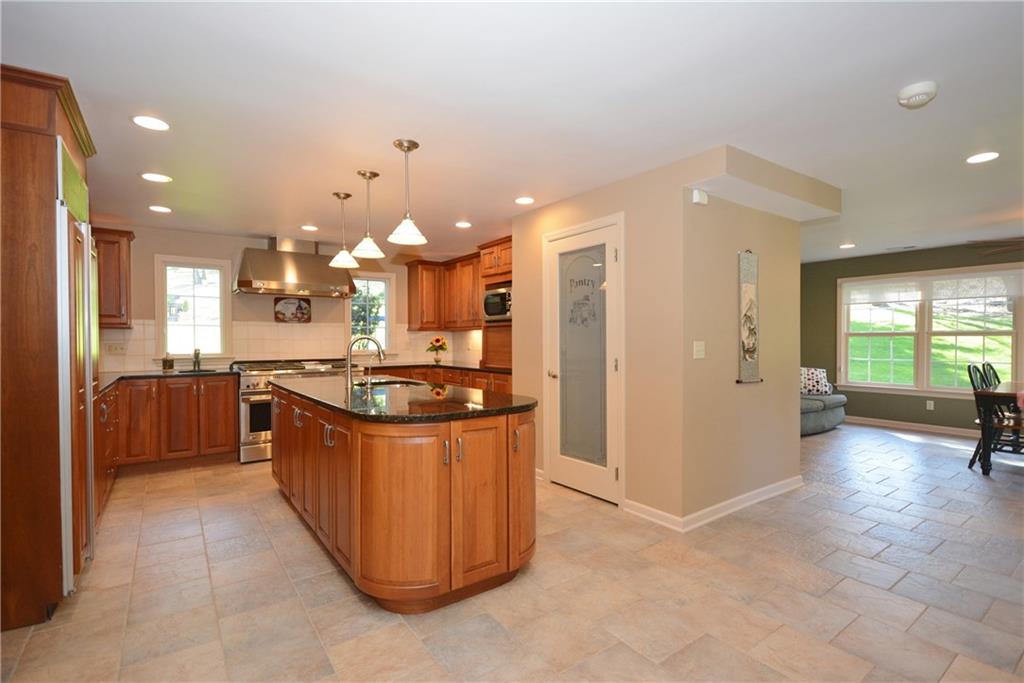 This large kitchen is a cook's dream!  Wow!  Custom cabinetry, spacious counter space, island, large pantry, high end appliances, granite counter tops, tiled backsplash, recessed lighting, pendant lighting.  Bright eat-in area.
