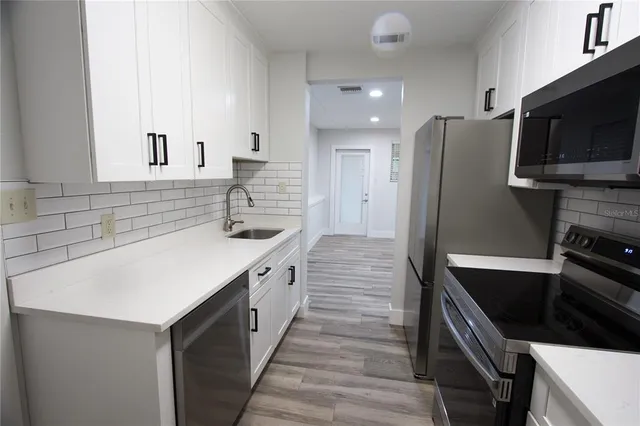 a kitchen with stainless steel appliances a sink stove and refrigerator