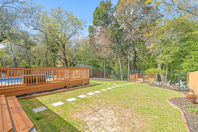 a view of a yard with wooden deck and a bench