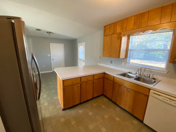 a kitchen with stainless steel appliances granite countertop a sink a refrigerator and a window