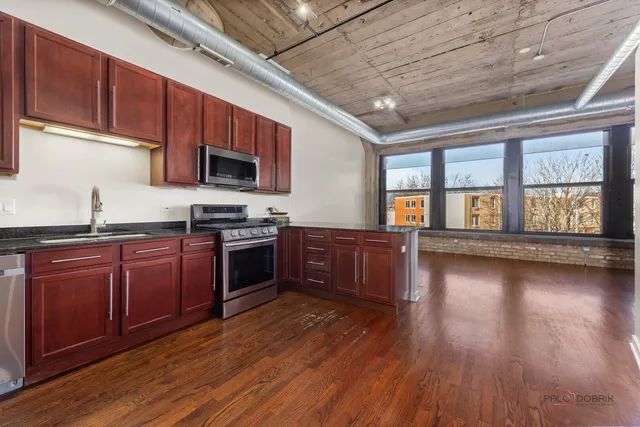 a kitchen with stainless steel appliances granite countertop wooden floors a stove and a microwave