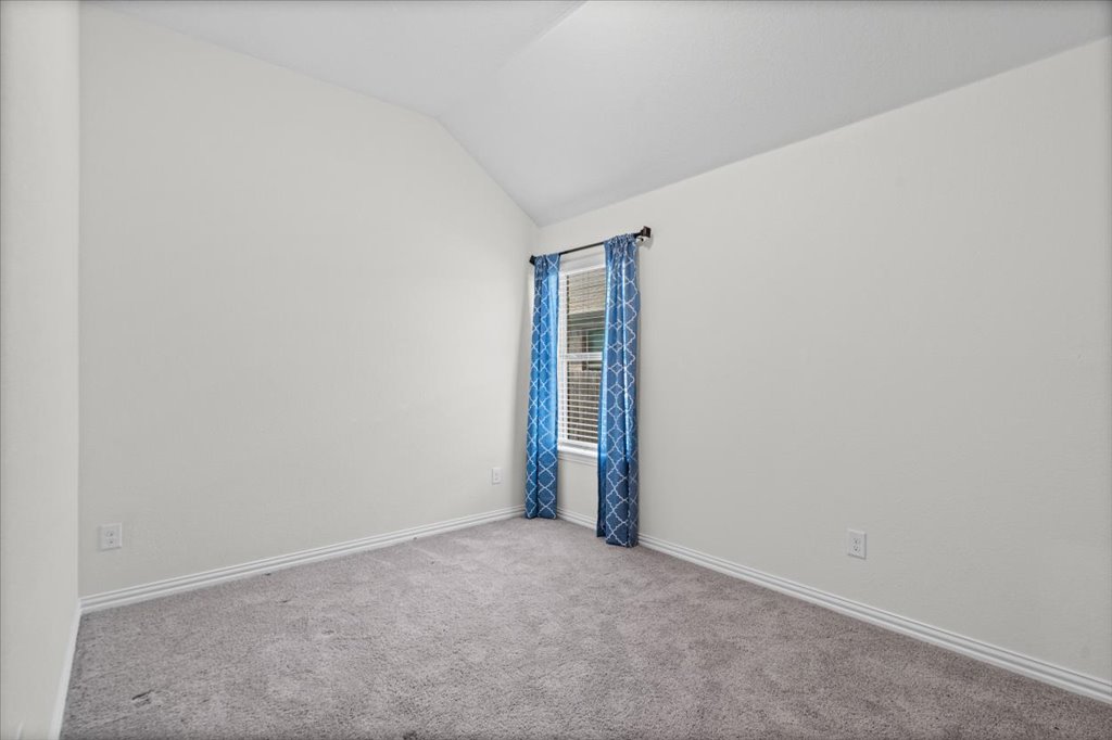 277 Spinnaker Loop Kyle, TX 78640 - Photo 27 of 38 A quiet bedroom featuring plush carpeting, vaulted ceilings, and a sun-filled window with blinds.