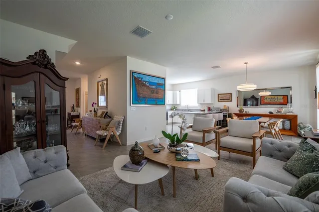 a living room with furniture kitchen view and a wooden floor