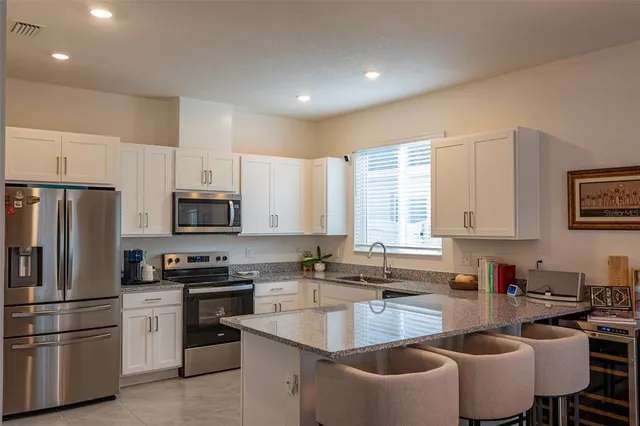 a kitchen with kitchen island a stove a sink a refrigerator a dining table and chairs