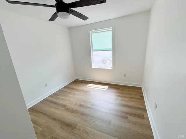an empty room with wooden floor cabinet and windows