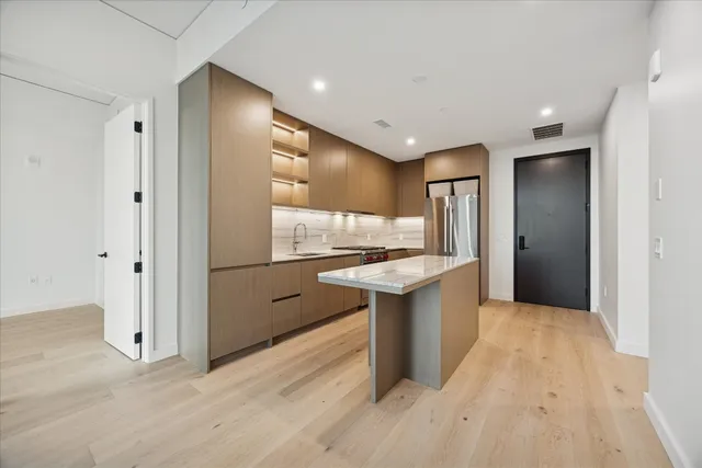 a kitchen with stainless steel appliances granite countertop a refrigerator a sink and a stove