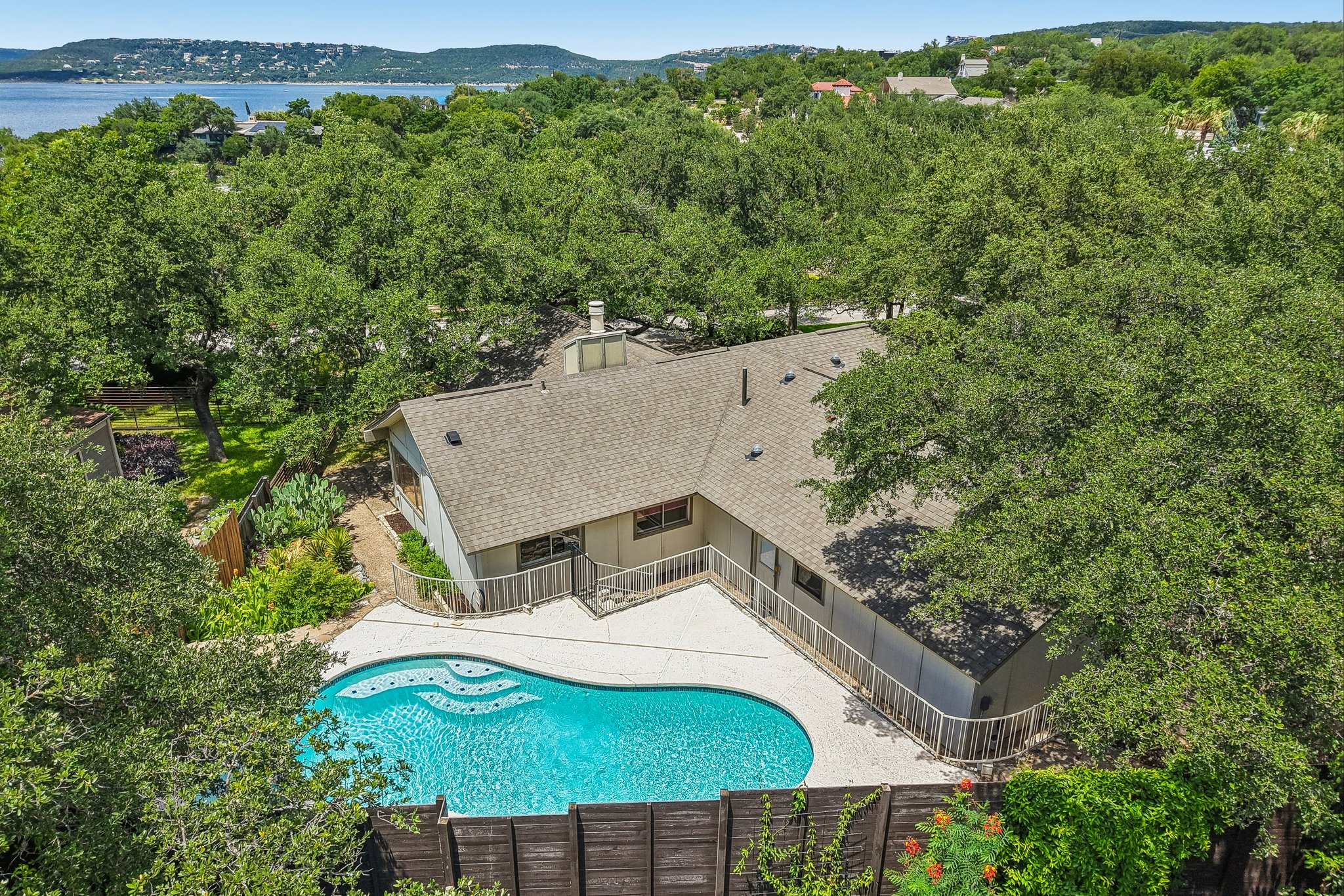 13101 Travis View Loop Austin, TX 78732 - Photo 2 of 27 An aerial perspective showcases a private pool, lush trees, and expansive water views in the distance.