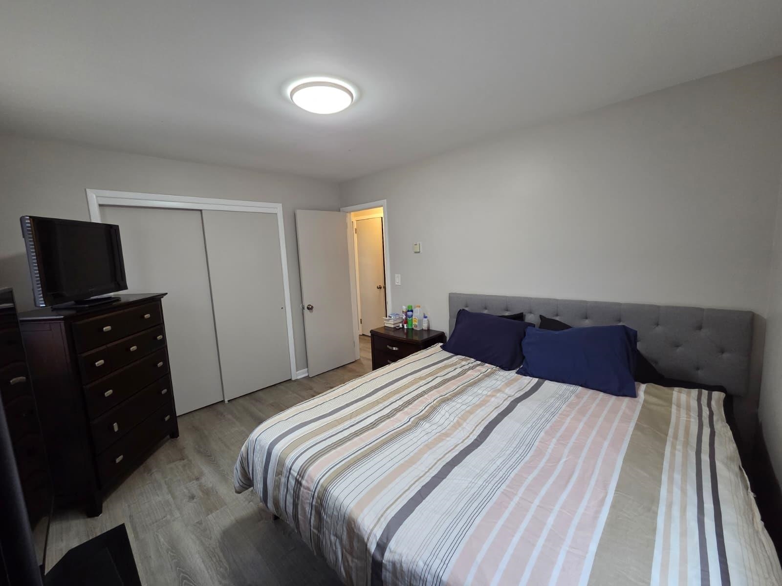 166 Carmita Avenue, Unit 2 Rutherford, NJ 07070 - Photo 11 of 27 a bedroom with a bed and a flat tv screen on a dresser