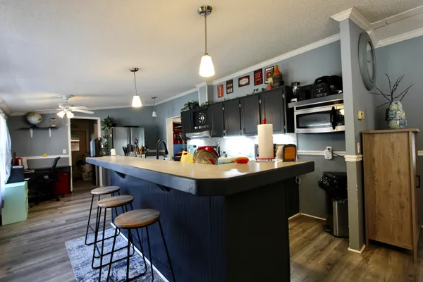a kitchen with stainless steel appliances kitchen island a table chairs in it and wooden floors