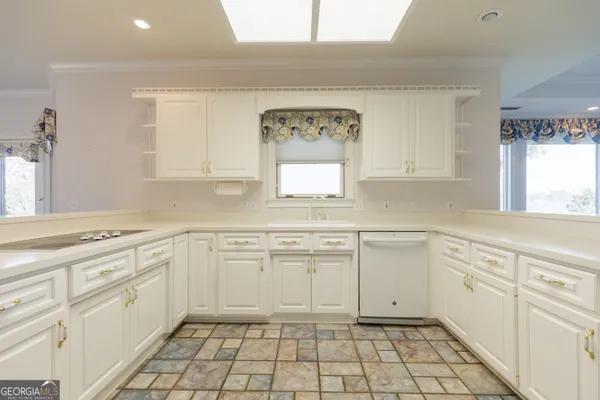 a kitchen with white cabinets appliances and a window