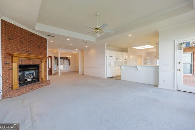 a view of a livingroom with a fireplace a ceiling fan and windows