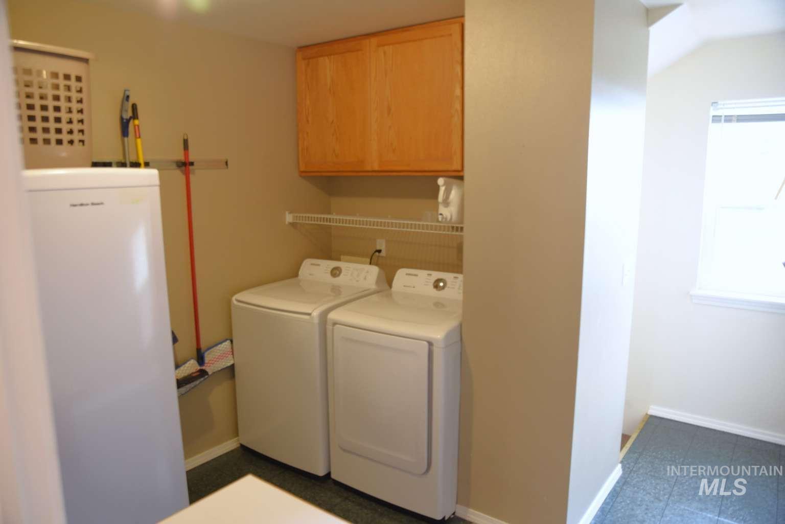1065 Loafer Lane Weiser, ID 83672 - Photo 17 of 36 Laundry area featuring cabinet space, washing machine and clothes dryer, and dark flooring