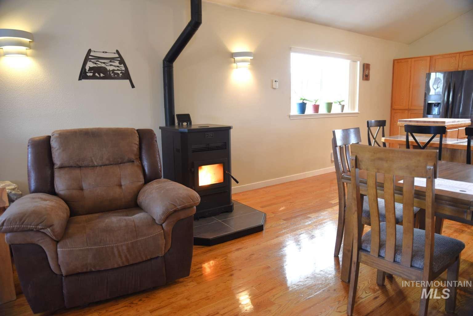 1065 Loafer Lane Weiser, ID 83672 - Photo 10 of 36 Dining space with light wood-style floors, vaulted ceiling, and a wood stove