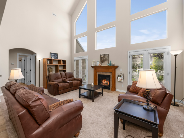 255 East 1200 North Mapleton, UT 84664 - Photo 3 of 37 Living area featuring a vaulted ceiling with multiple large windows, a wood-surround fireplace with a stone hearth, and double glass-paneled doors with integrated blinds