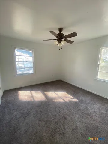 an empty room with a window and a fan