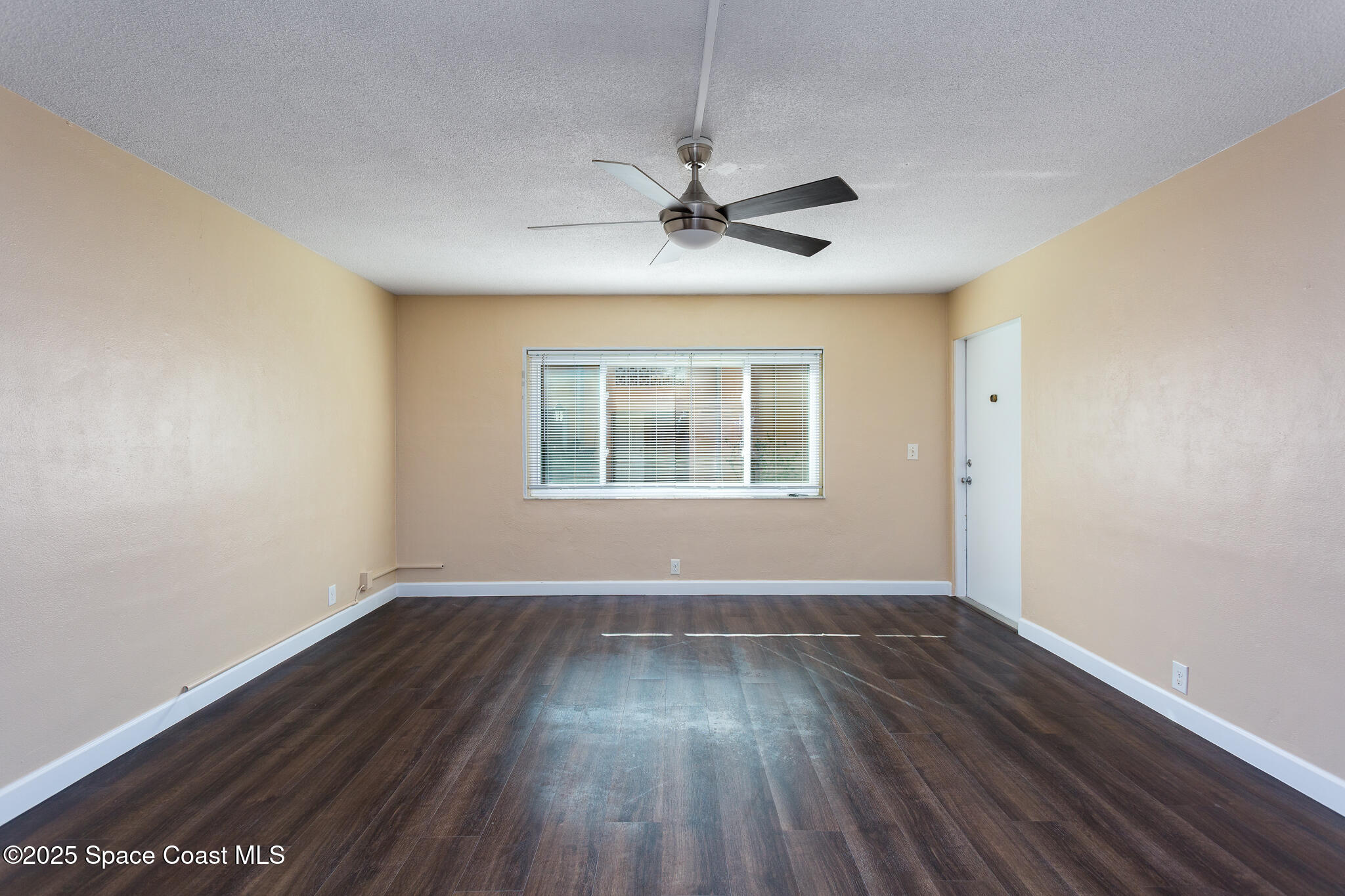 1700 Atlantic Street, Unit 9 Melbourne Beach, FL 32951 - Photo 6 of 30 an empty room with wooden floor ceiling fan and windows