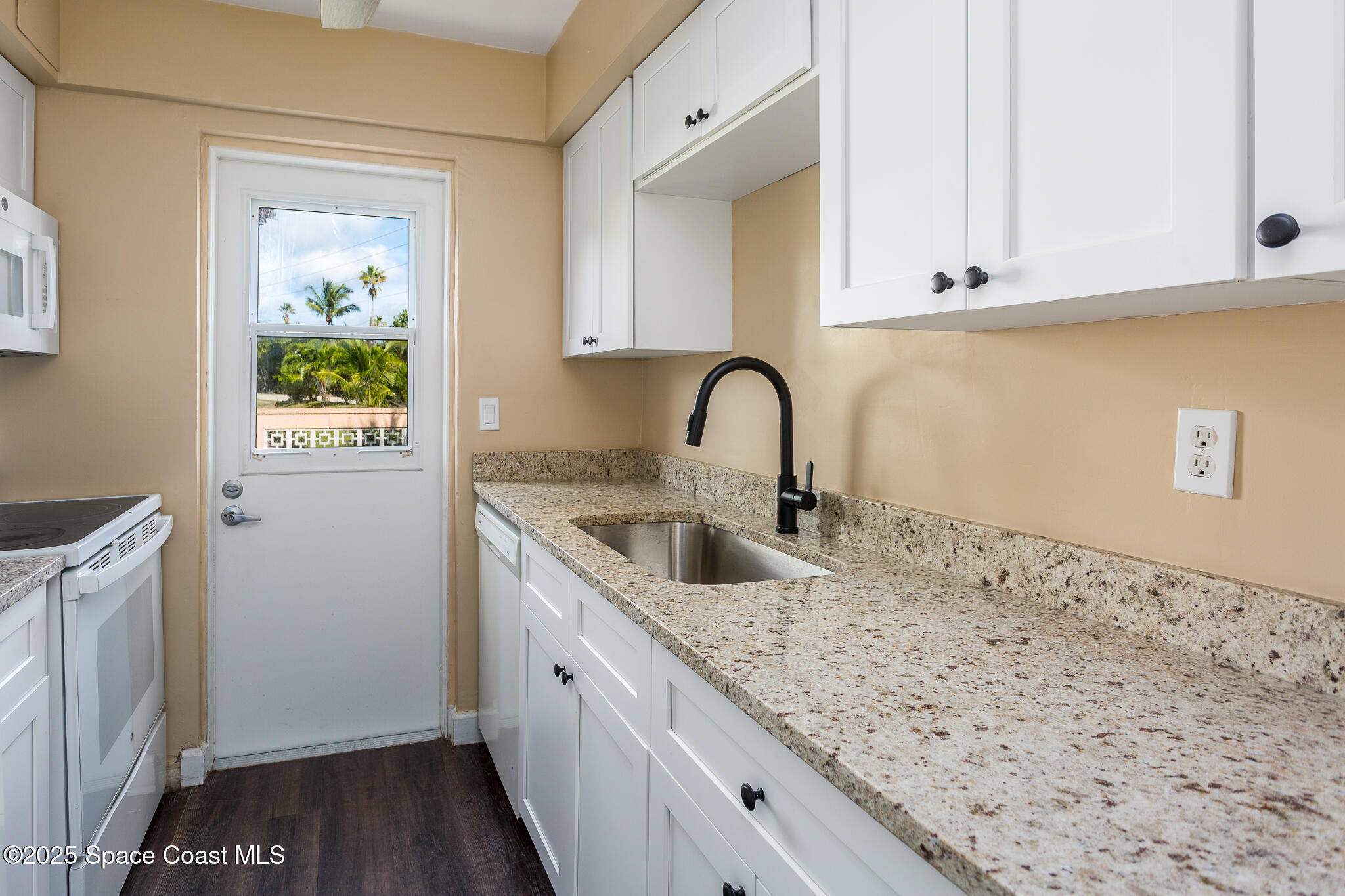 1700 Atlantic Street, Unit 9 Melbourne Beach, FL 32951 - Photo 8 of 30 a kitchen with granite countertop a sink and a stove top oven
