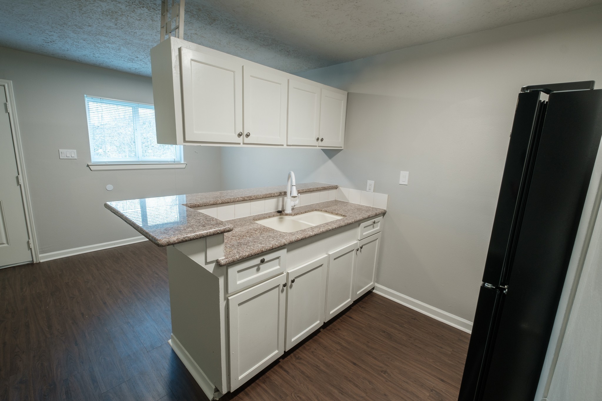 a kitchen with granite countertop a sink and a refrigerator