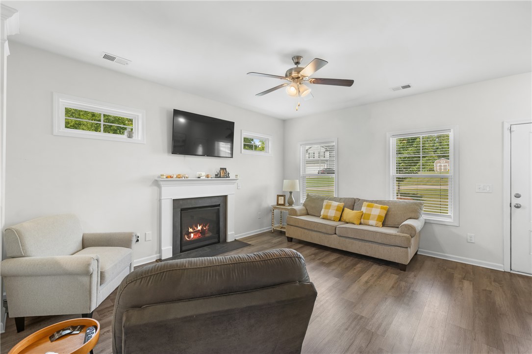 768 Rocky Ridge Circle Seneca, SC 29678 - Photo 7 of 30 A well-lit living space features rich hardwood flooring and a cozy fireplace, perfect for gathering.