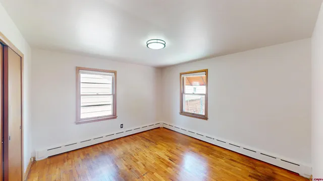 an empty room with wooden floor and windows