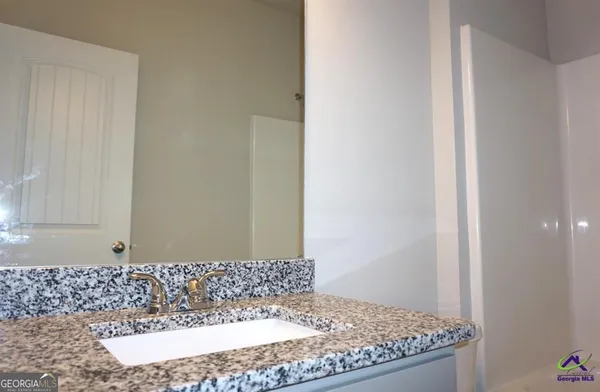 a bathroom with a granite countertop sink and a mirror