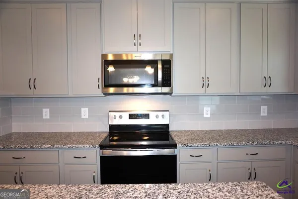 a kitchen with stainless steel appliances granite countertop white cabinets and a stove