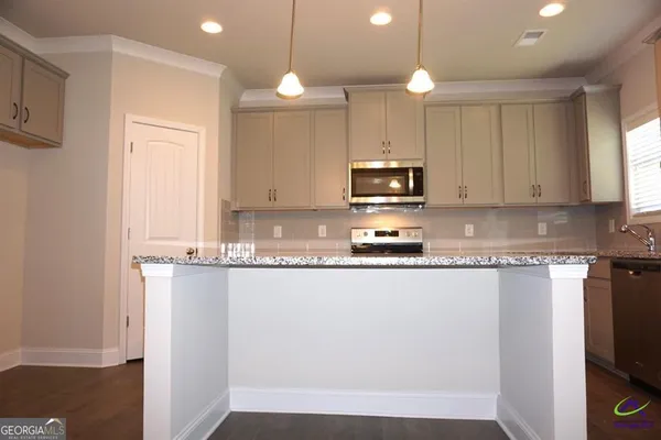 a large kitchen with granite countertop a stove a sink and a microwave