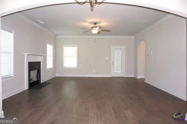 an empty room with wooden floor fan and window
