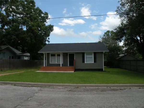 a front view of a house with a garden and trees