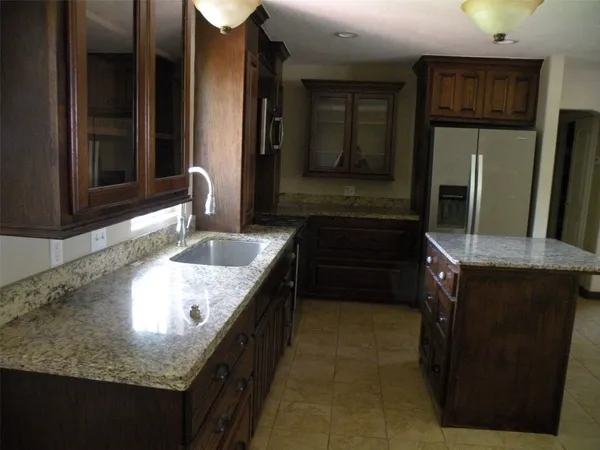 a kitchen with granite countertop a sink stove and refrigerator