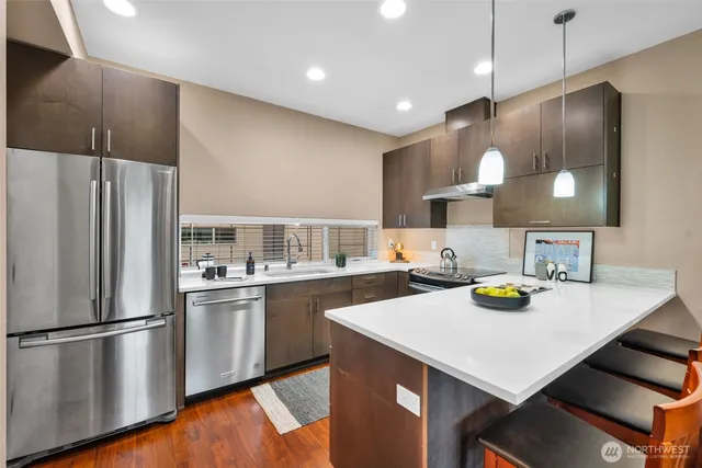 a kitchen with a refrigerator a sink and wooden floor