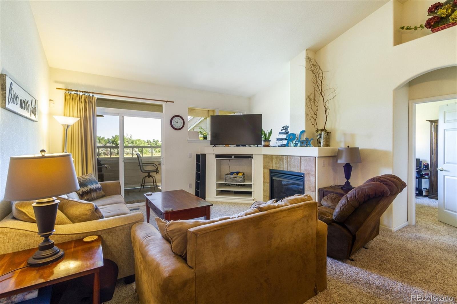6697 South Reed Way, Unit B Littleton, CO 80123 - Photo 16 of 35 a living room with furniture a fireplace and a flat screen tv