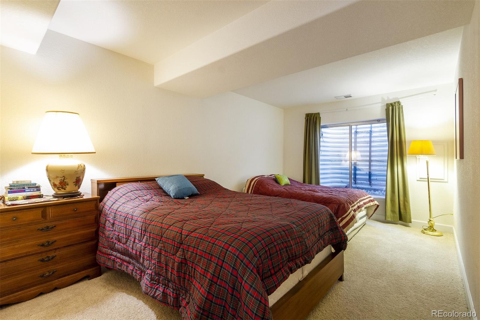 6697 South Reed Way, Unit B Littleton, CO 80123 - Photo 19 of 35 a bedroom with a bed and lamp