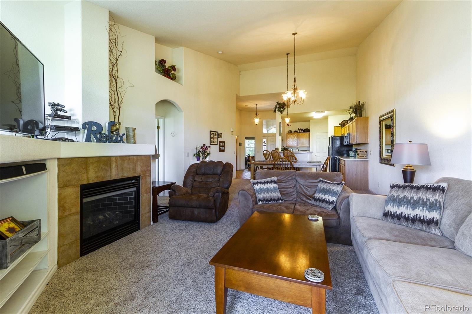 6697 South Reed Way, Unit B Littleton, CO 80123 - Photo 10 of 35 a living room with furniture a fireplace and a chandelier