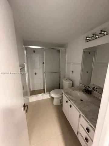 a spacious bathroom with a granite countertop sink a toilet a mirror and shower