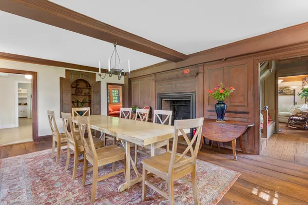 a dining room with furniture wooden floor a rug a potted plant and a chandelier
