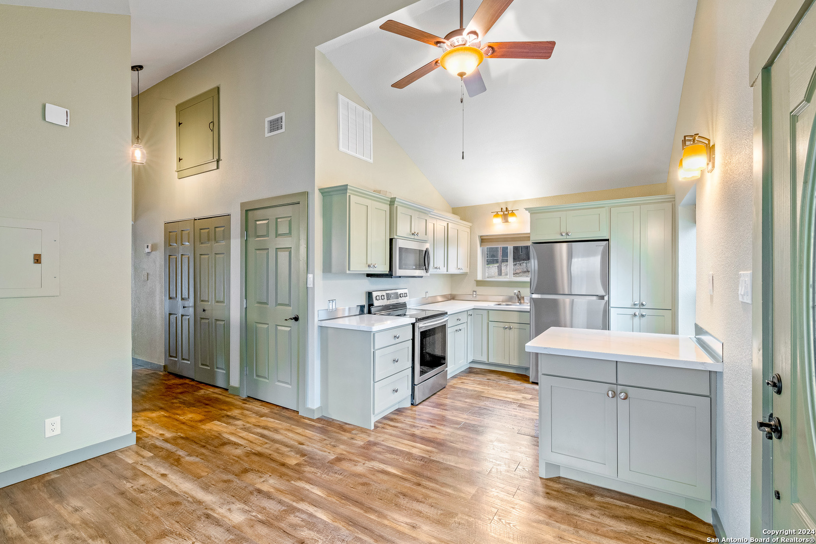 a kitchen with a refrigerator a sink cabinets and wooden floor