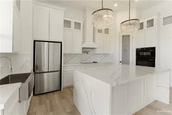 a kitchen with stainless steel appliances granite countertop a refrigerator a oven a sink and white cabinets with wooden floor