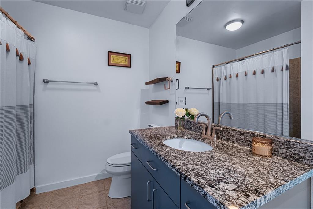 250 Pharr Road Northeast, Unit 310 Atlanta, GA 30305 - Photo 14 of 37 a bathroom with a granite countertop sink a toilet and a mirror