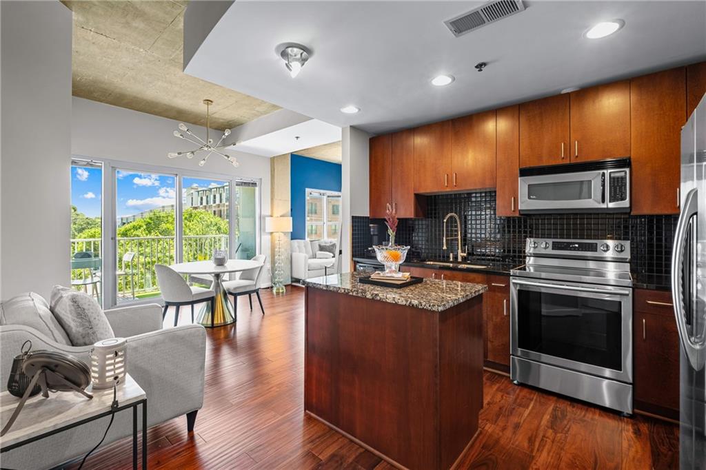 250 Pharr Road Northeast, Unit 310 Atlanta, GA 30305 - Photo 3 of 37 a kitchen with stainless steel appliances granite countertop a stove top oven a sink dishwasher a dining table and chairs with wooden floor