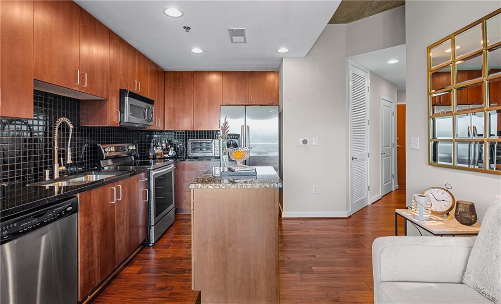 250 Pharr Road Northeast, Unit 310 Atlanta, GA 30305 - Photo 4 of 37 a kitchen with stainless steel appliances granite countertop a refrigerator a sink dishwasher a stove and a dining table with wooden floor