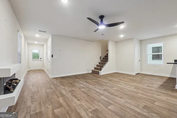 a view of an empty room with wooden floor and a window