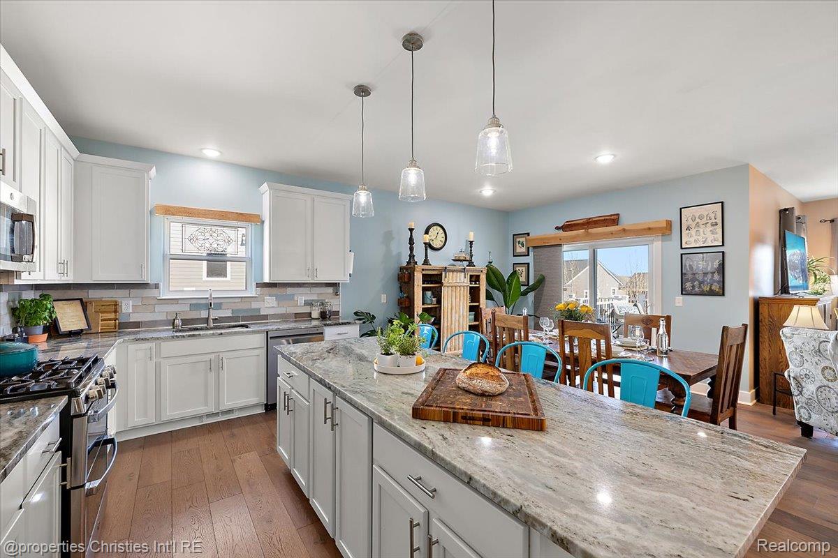 913 Ridge Road South Canton, MI 48188 - Photo 20 of 51 Kitchen featuring dark wood-style floors, white cabinetry, decorative backsplash, and a kitchen island