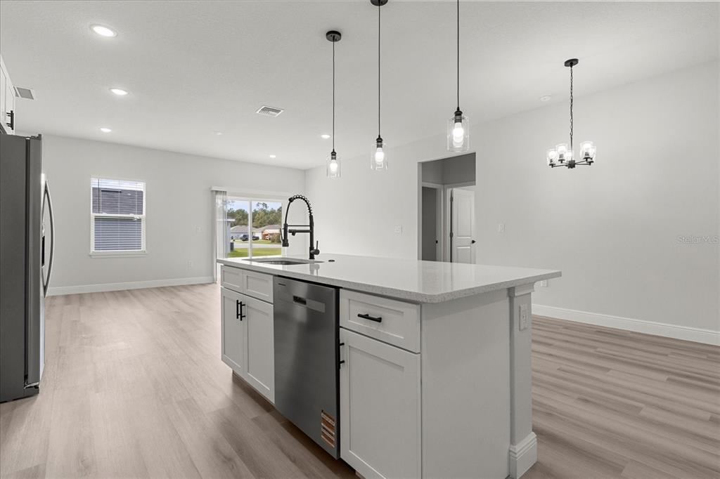 4016 Southwest 151st Street Ocala, FL 34473 - Photo 25 of 32 a kitchen with stainless steel appliances granite countertop a sink a stove a refrigerator and white cabinets with wooden floor