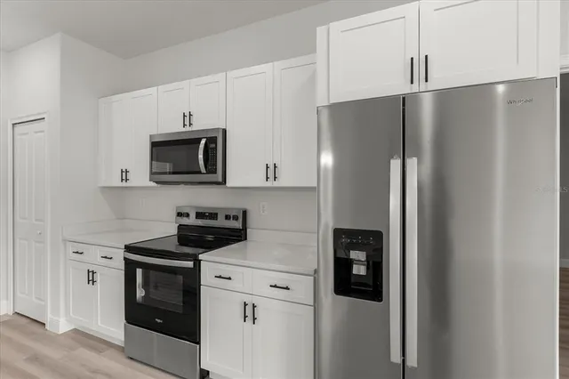 a kitchen with stainless steel appliances white cabinets and a refrigerator